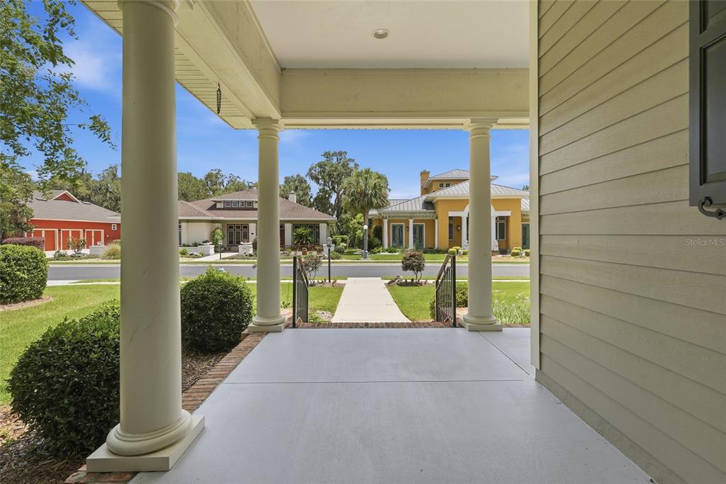 A covered front porch with white columns overlooks a suburban street and neighboring houses — 3926 SW 69TH AVENUE, GAINESVILLE, FL