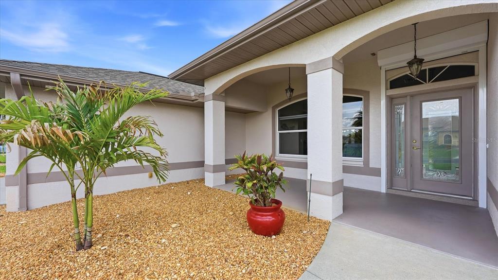 The exterior of a house features a covered entryway, a palm tree, and gravel landscaping — 828 ROTONDA CIRCLE, ROTONDA WEST, FL
