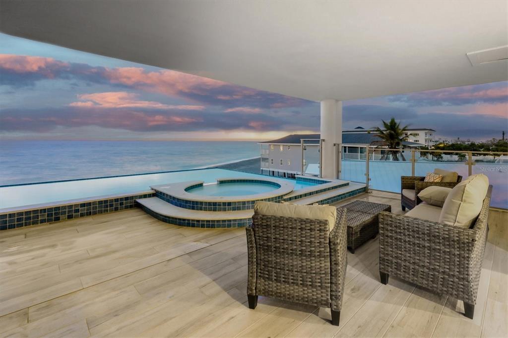An outdoor balcony features a hot tub, an infinity pool, and wicker patio furniture — 2708 N BEACH ROAD UNIT 3, ENGLEWOOD, FL