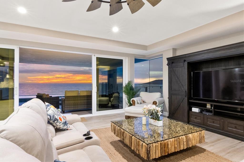 A living room features a glass-topped driftwood coffee table, a large television, and ocean views — 2708 N BEACH ROAD UNIT 3, ENGLEWOOD, FL