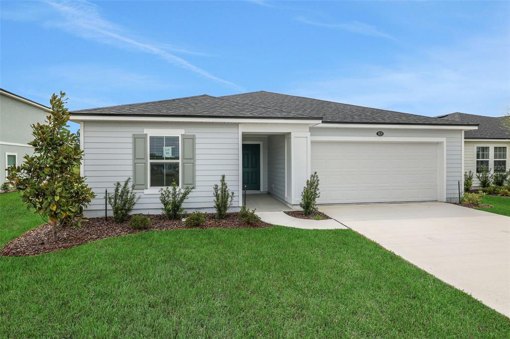 A single-story house with light gray siding, a two-car garage, and a green front door — 3829 HOLSTEIN WAY, GREEN COVE SPRINGS, FL