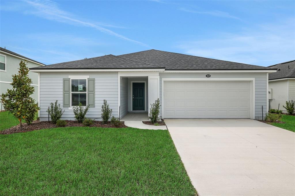 A single-story house with light blue siding, a two-car garage, and a front walkway — 3829 HOLSTEIN WAY, GREEN COVE SPRINGS, FL