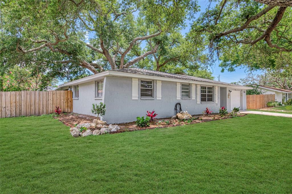 A single-story gray house with white shutters sits on a lawn under large oak trees — 361 FALKLAND ROAD, VENICE, FL