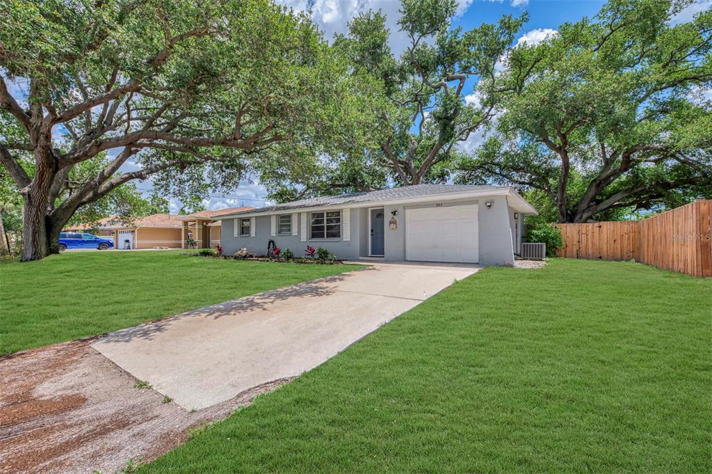 A single-story gray house with a concrete driveway and large oak trees in the yard — 361 FALKLAND ROAD, VENICE, FL