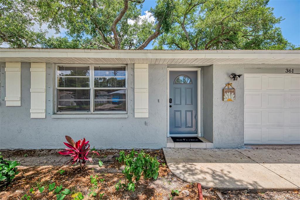 The exterior of a gray house features a blue front door and a white garage — 361 FALKLAND ROAD, VENICE, FL