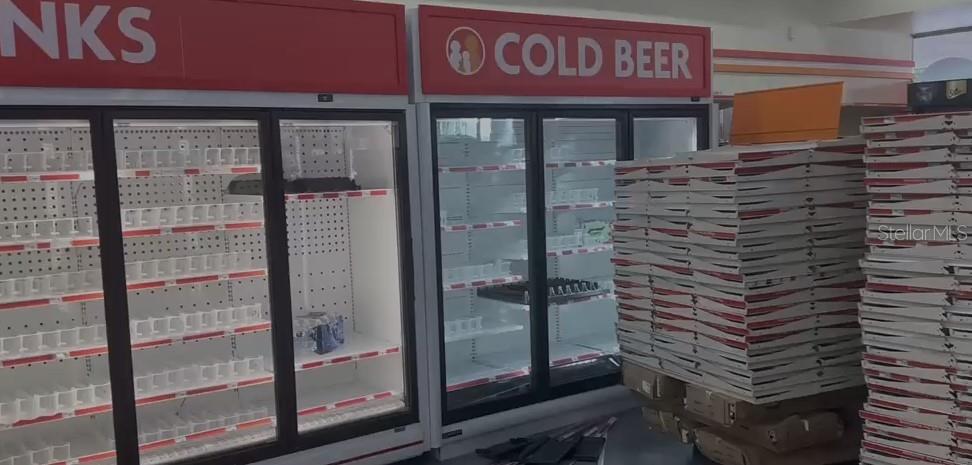 Empty commercial refrigerators stand next to large stacks of white boxes in a retail space — 1727 E BUSCH BOULEVARD, TAMPA, FL