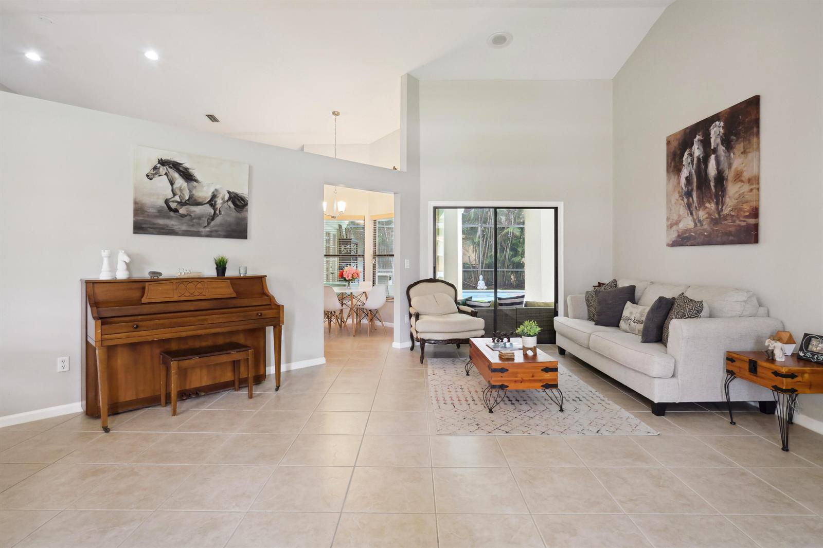 A living room features a piano, a sofa, a coffee table, and a view of a pool — 13823 Callington Drive, Wellington FL 33414, WELLINGTON, FL