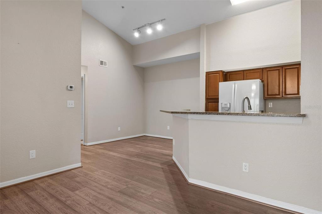 An interior view shows a kitchen with wood cabinets and a breakfast bar overlooking a room — 4174 CENTRAL SARASOTA PARKWAY UNIT # 233, SARASOTA, FL
