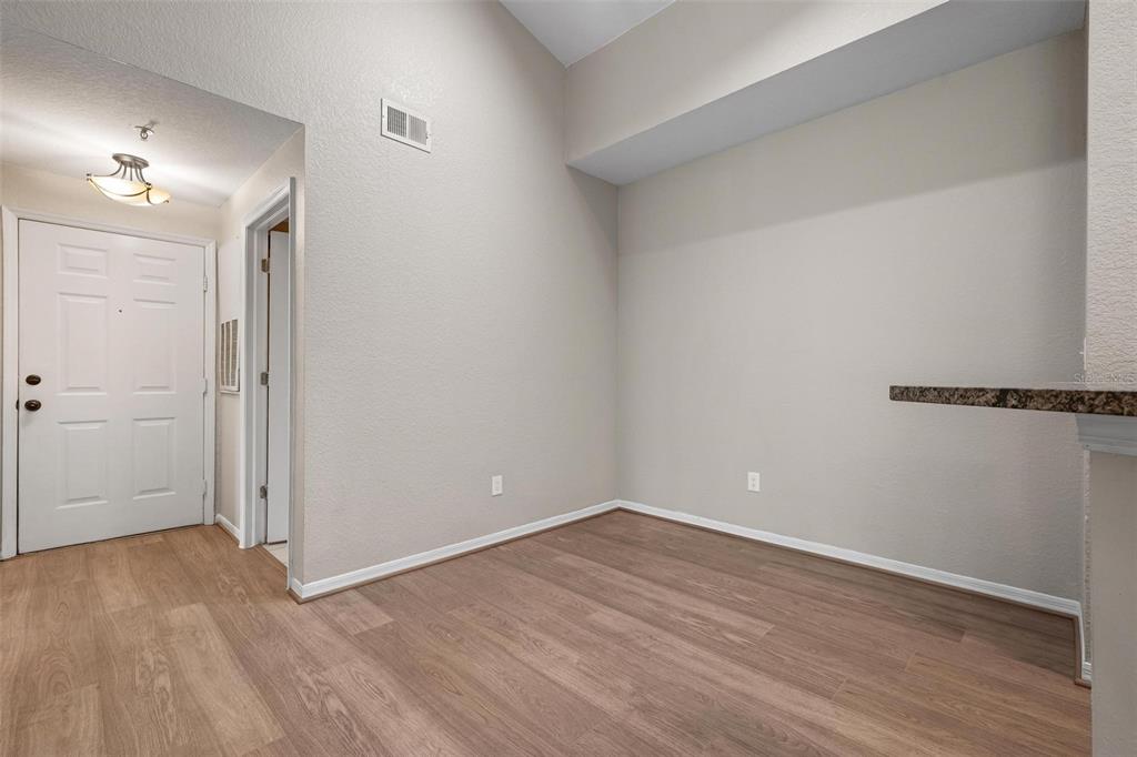 An empty room with light-colored walls, wood-look flooring, and a granite-topped breakfast bar — 4174 CENTRAL SARASOTA PARKWAY UNIT # 233, SARASOTA, FL