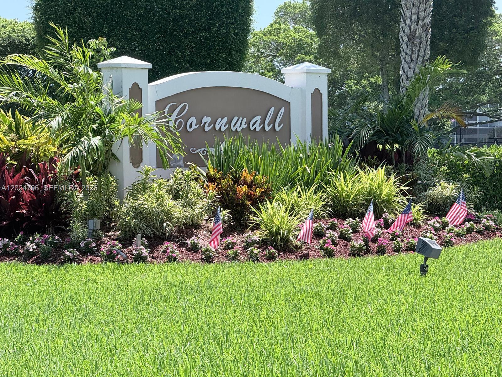 A white monument sign for Cornwall sits in a landscaped garden with small American flags — 3069 Cornwall D # 3069, Boca Raton FL 33434, BOCA RATON, FL