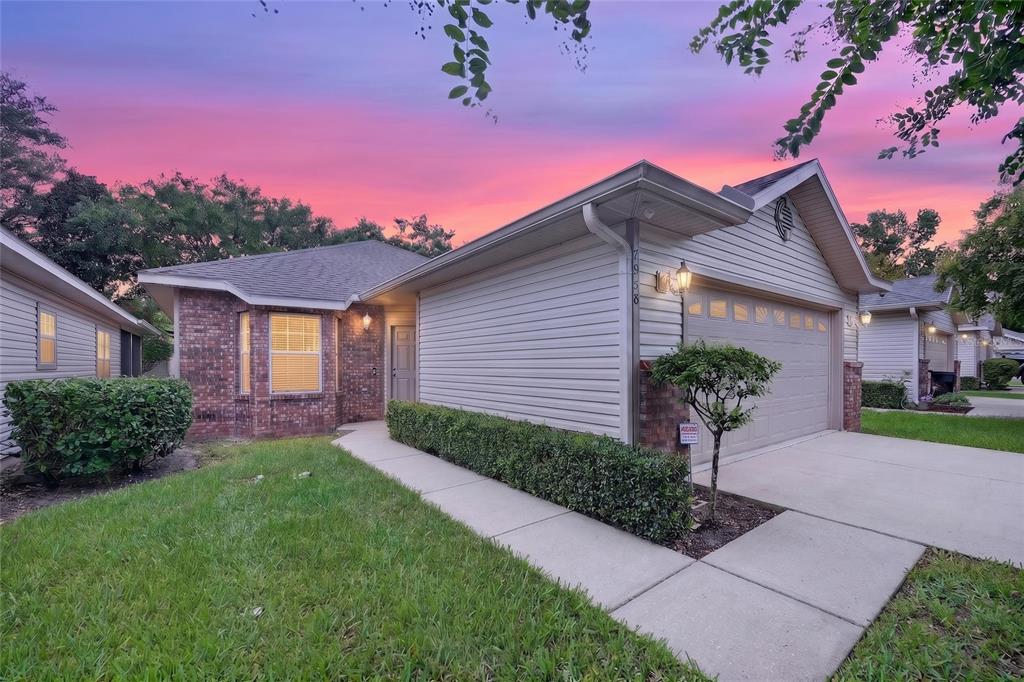 A single-story house with beige siding, a brick facade, and a two-car garage at sunset — 7958 NW 49TH WAY, GAINESVILLE, FL