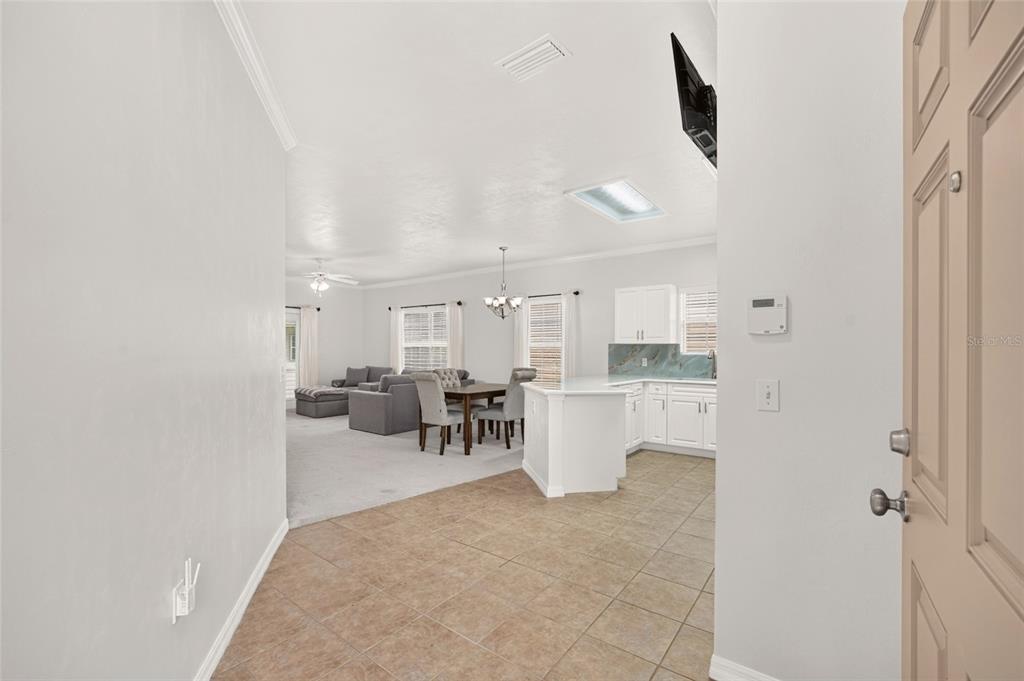 A view from an entryway into an open-concept kitchen and living area with tile flooring — 7958 NW 49TH WAY, GAINESVILLE, FL