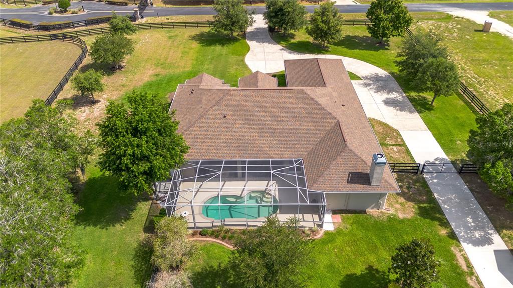 An aerial view shows a house with a screened-in pool and a long concrete driveway — 6957 NW 54TH LOOP, OCALA, FL