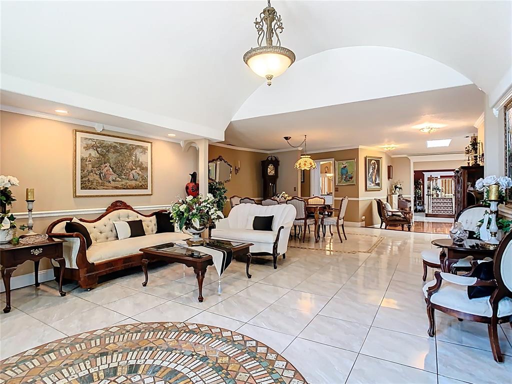 A spacious living and dining area features tiled floors, arched ceilings, and traditional furniture — 5852 MEDINAH WAY, ORLANDO, FL