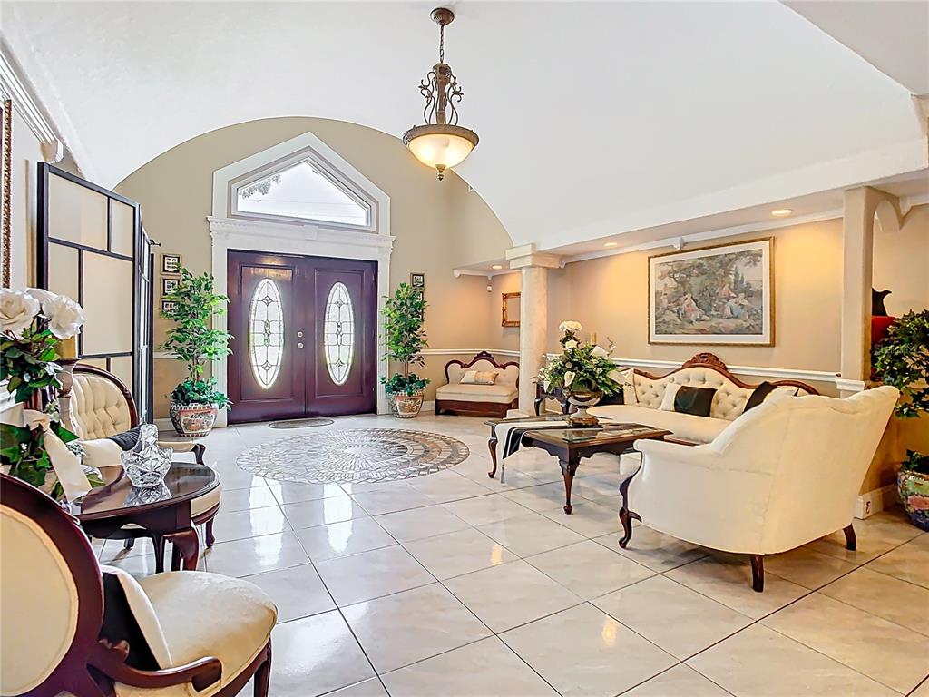 A spacious foyer features a vaulted ceiling, tiled floors, a chandelier, and formal seating areas — 5852 MEDINAH WAY, ORLANDO, FL