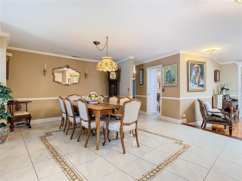 A dining room features a wooden table with six chairs, a chandelier, and tiled flooring — 5852 MEDINAH WAY, ORLANDO, FL