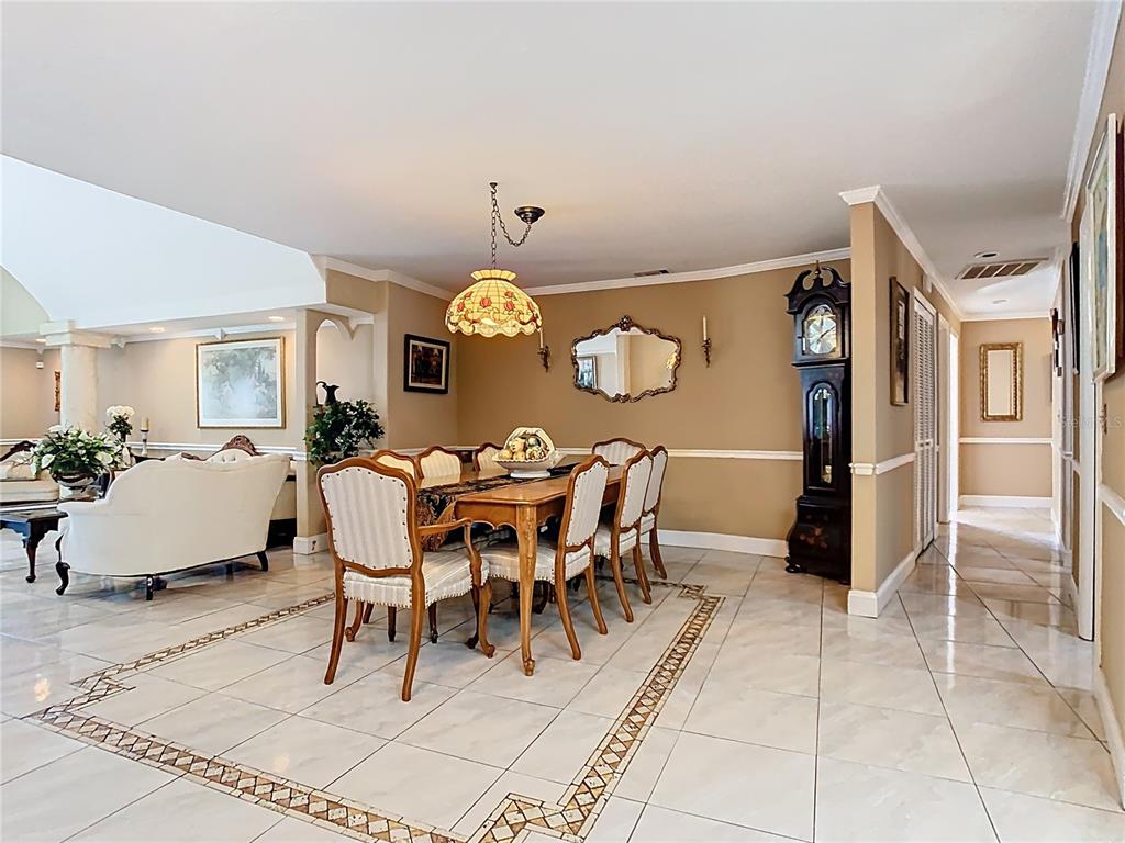 A dining room features a wooden table, upholstered chairs, a grandfather clock, and tile flooring — 5852 MEDINAH WAY, ORLANDO, FL