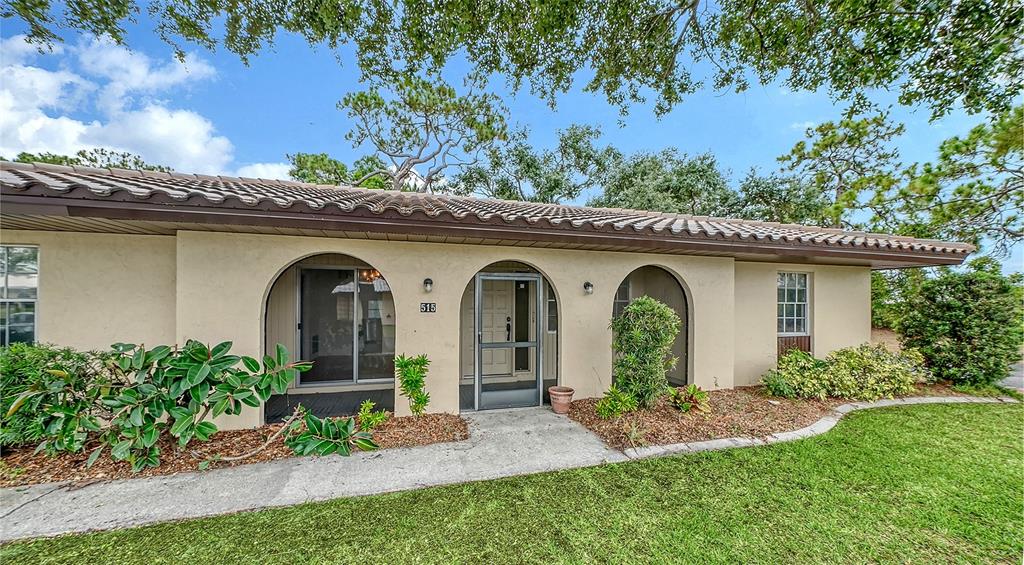 A single-story house exterior features arched entryways, a tiled roof, and a concrete walkway — 515 ROUSSEAU DRIVE, NOKOMIS, FL