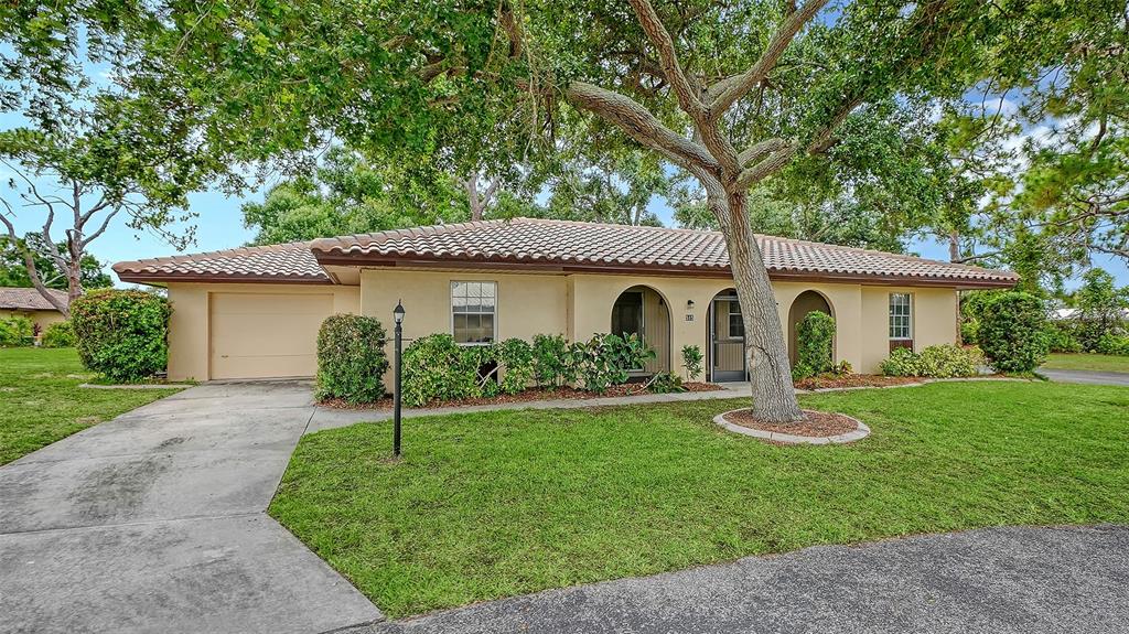 A single-story house with a tile roof, garage, and arched entryway sits on a lawn — 515 ROUSSEAU DRIVE, NOKOMIS, FL