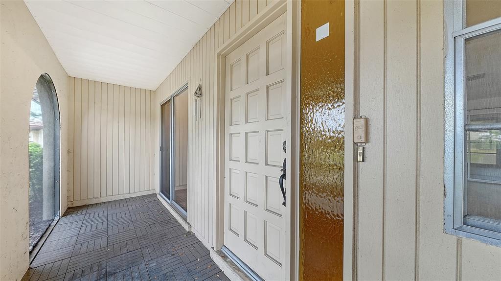A covered porch features a white paneled front door, a side window, and tiled flooring — 515 ROUSSEAU DRIVE, NOKOMIS, FL