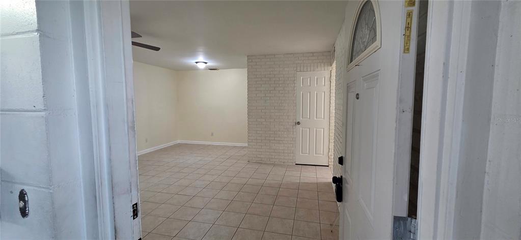 An interior view shows a tiled room with a white brick wall and a doorway — 6717 MORNAY CIRCLE, TAMPA, FL