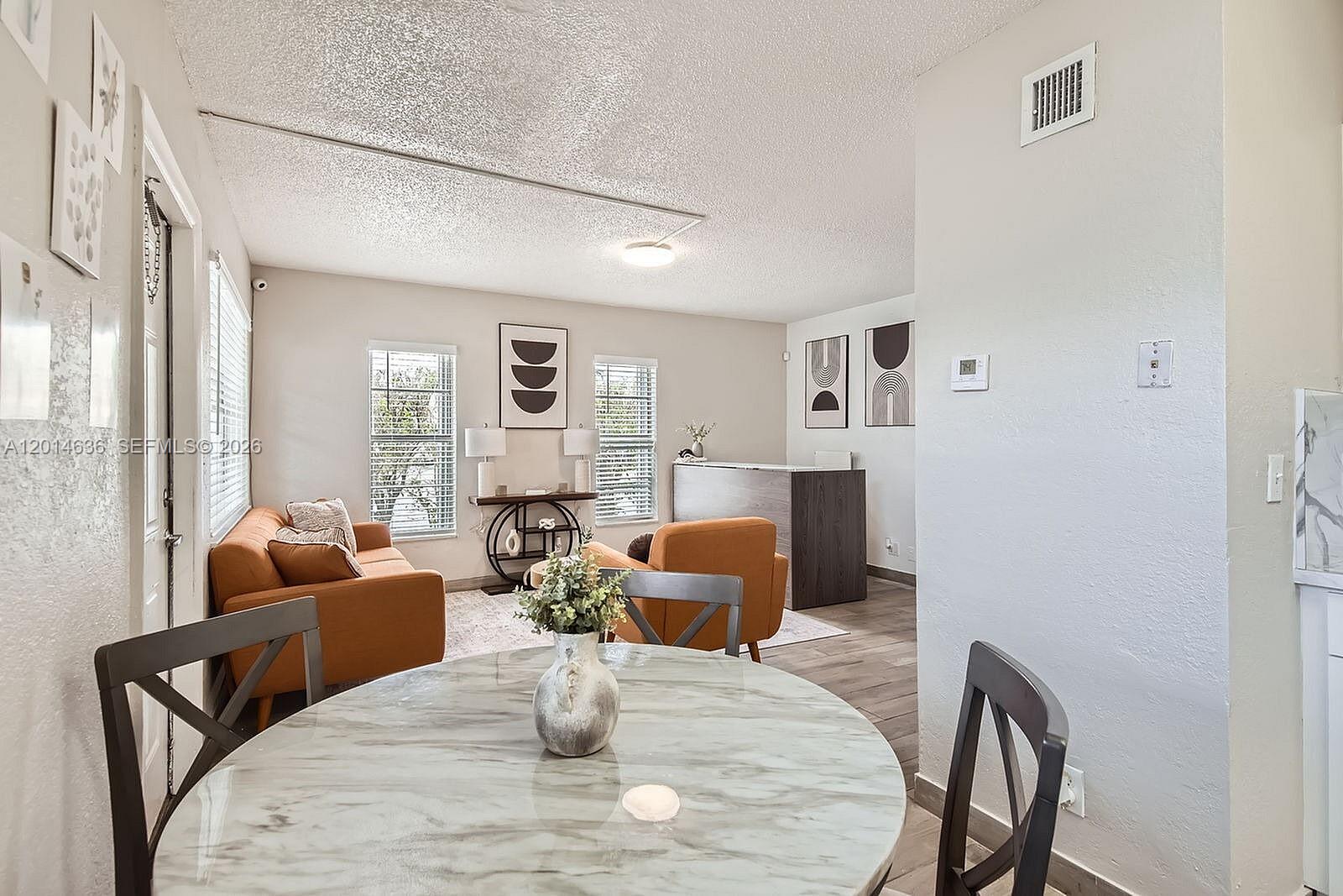 A dining area with a marble table overlooks a living room with orange furniture — 311 NW 42ND CT # 101, Pompano Beach FL 33064, POMPANO BEACH, FL