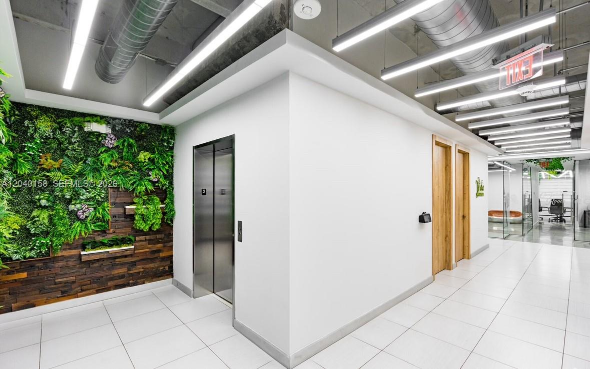 An office hallway features an elevator, a green wall, and modern linear ceiling lights — 2550 NW 100th Ave, Doral FL 33172, DORAL, FL