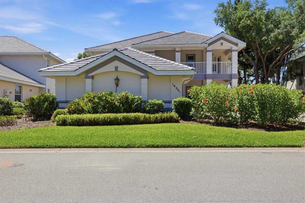 A two-story house with a tiled roof, a balcony, and landscaping in front — 14061 WILLOW GLEN COURT UNIT 239, PORT CHARLOTTE, FL