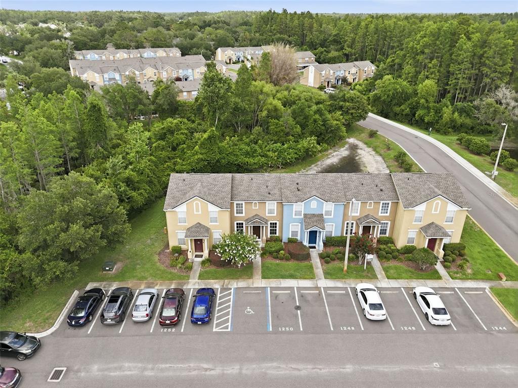 An aerial view shows a multi-unit townhouse building with a parking lot in front — 1250 CHARLESWORTH DRIVE, WESLEY CHAPEL, FL