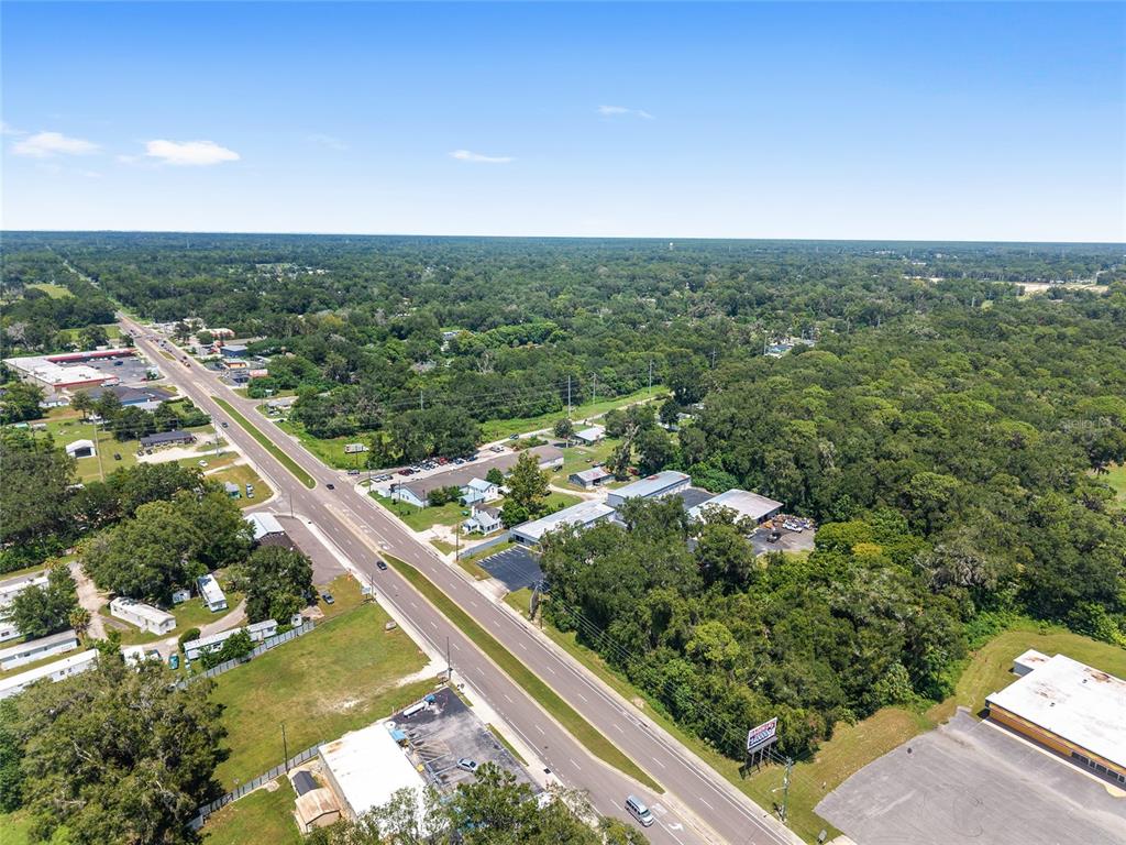 An aerial view shows a multi-lane road running through a wooded area with commercial buildings — 3007 NE JACKSONVILLE ROAD, OCALA, FL