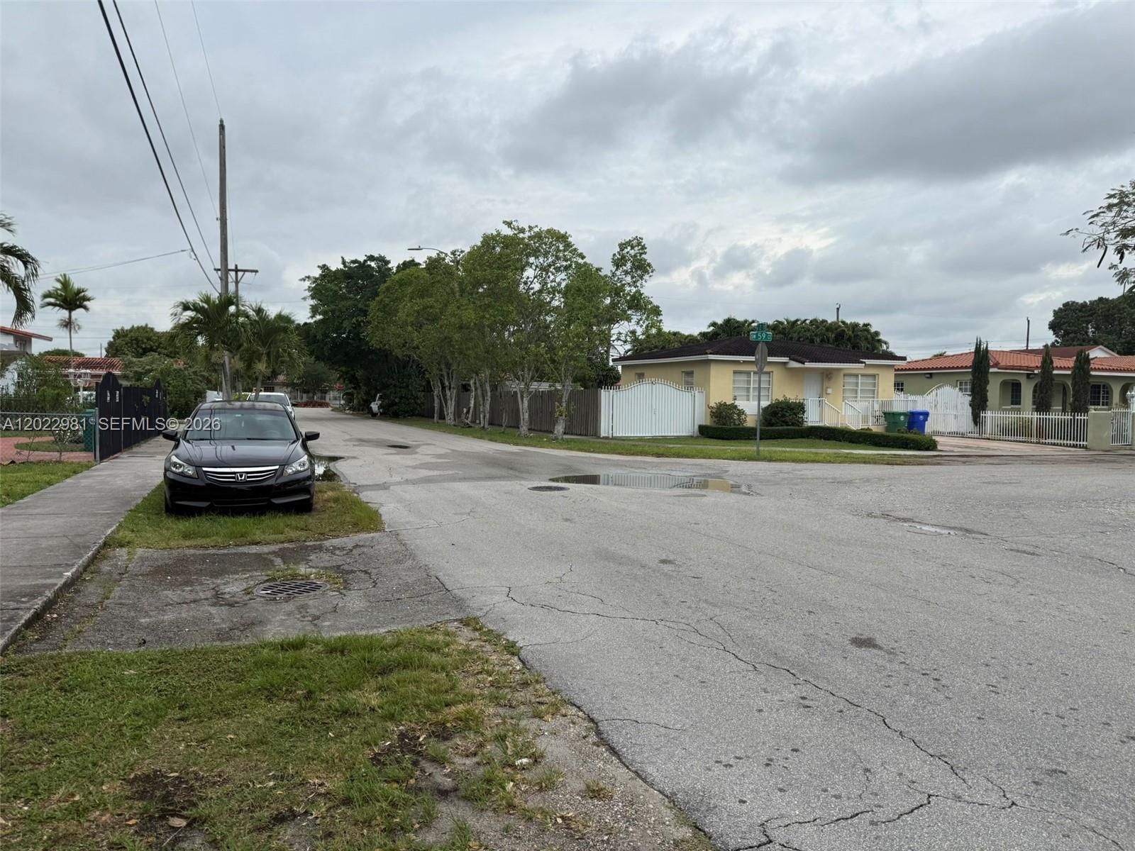 A black sedan is parked on the grass beside a street in a residential neighborhood — 5940 SW 2nd St, Miami FL 33144, MIAMI, FL