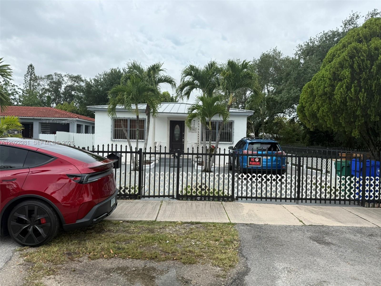 A white single-story house with a metal roof sits behind a black metal fence — 5940 SW 2nd St, Miami FL 33144, MIAMI, FL