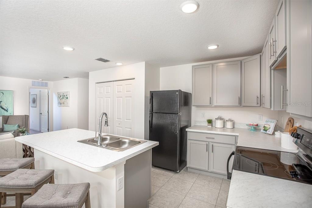 A kitchen features light gray cabinets, white countertops, a black refrigerator, and a center island — 3866 S FLORAL TERRACE, INVERNESS, FL