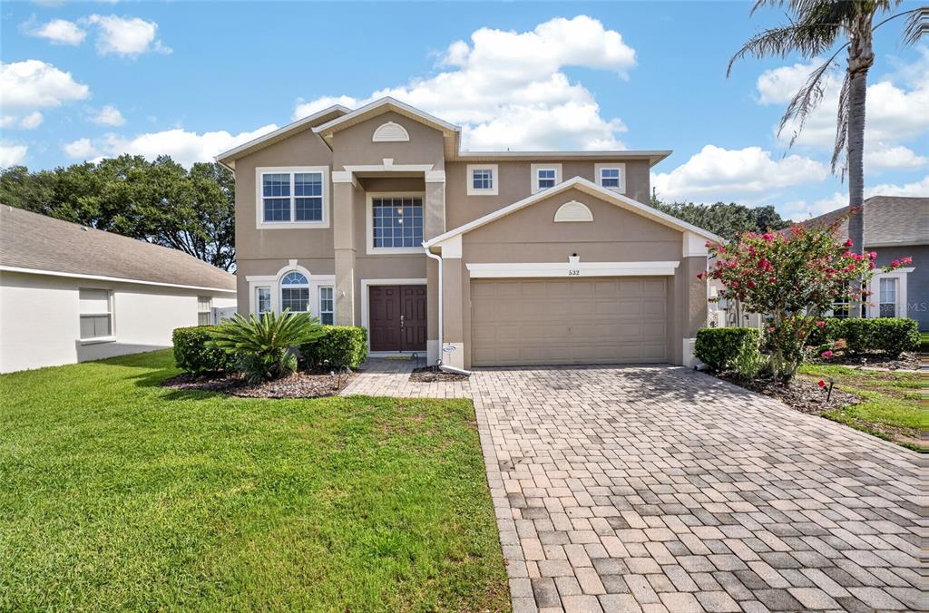 A two-story suburban house with a tan stucco exterior, a paved driveway, and a garage — 532 KILDRUMMY DRIVE, DAVENPORT, FL