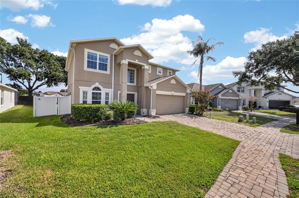 A two-story suburban house with a tan stucco exterior, a paved driveway, and a lawn — 532 KILDRUMMY DRIVE, DAVENPORT, FL