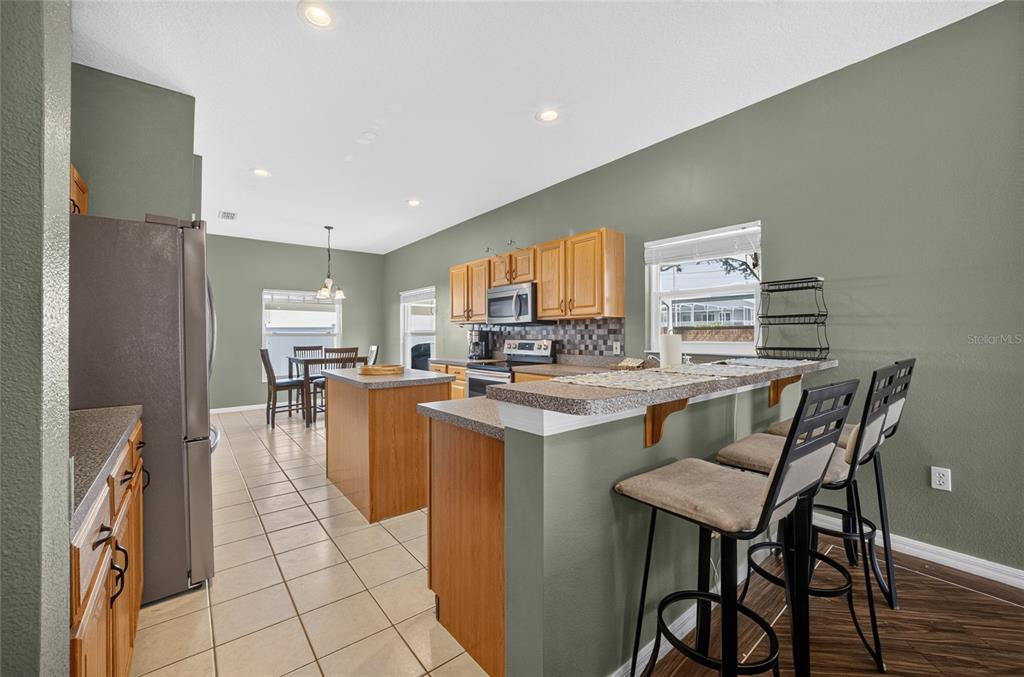 A kitchen features wood cabinets, a breakfast bar, an island, and tile flooring — 532 KILDRUMMY DRIVE, DAVENPORT, FL