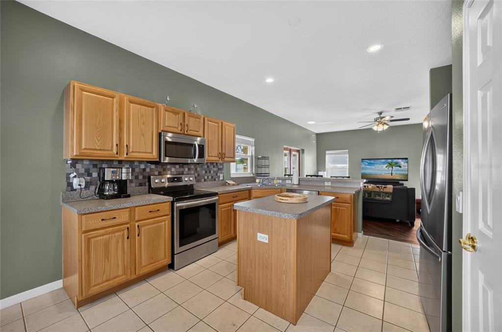 A kitchen with oak cabinets, stainless steel appliances, a center island, and tile flooring — 532 KILDRUMMY DRIVE, DAVENPORT, FL