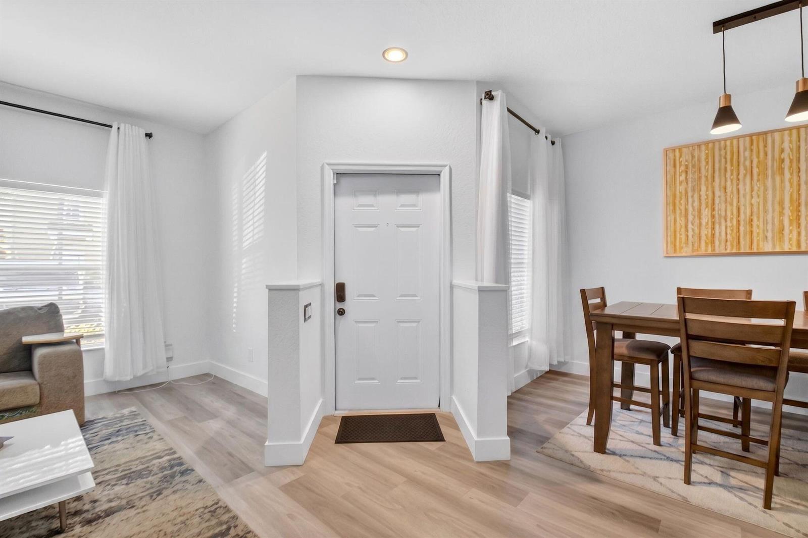A bright entryway features a white front door flanked by half-walls, wood-look flooring, and curtains — 173 Lake Monterey Circle, Boynton Beach FL 33426, BOYNTON BEACH, FL
