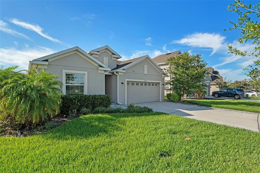 A single-story house with a beige stucco exterior, a two-car garage, and a manicured lawn — 8052 OLIVE BROOK DRIVE, WESLEY CHAPEL, FL