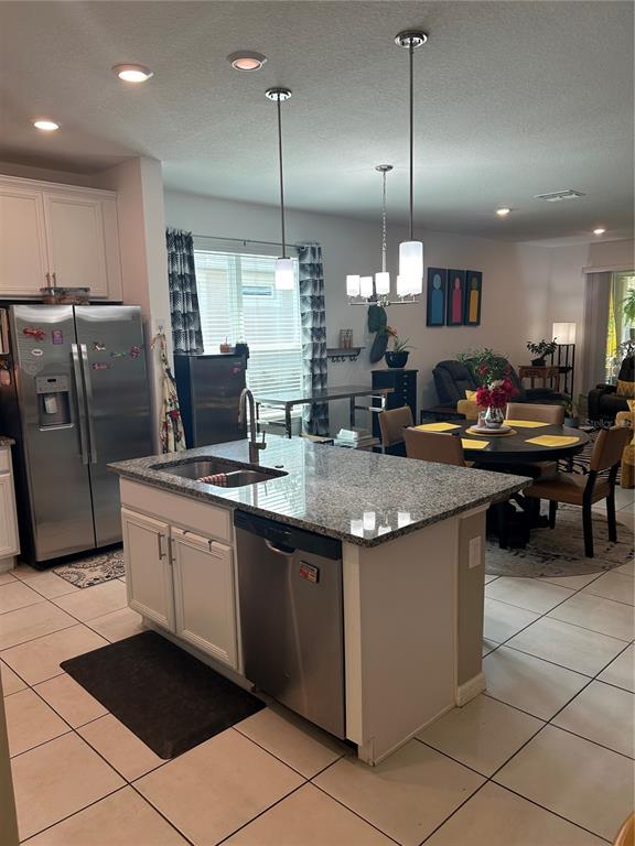 A kitchen with a granite-topped island, stainless steel appliances, and an adjacent dining area — 377 VESTRELLA DRIVE, KISSIMMEE, FL