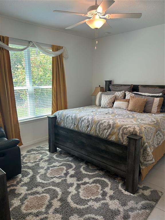 A bedroom features a dark wood bed frame, a patterned rug, and gold curtains — 377 VESTRELLA DRIVE, KISSIMMEE, FL