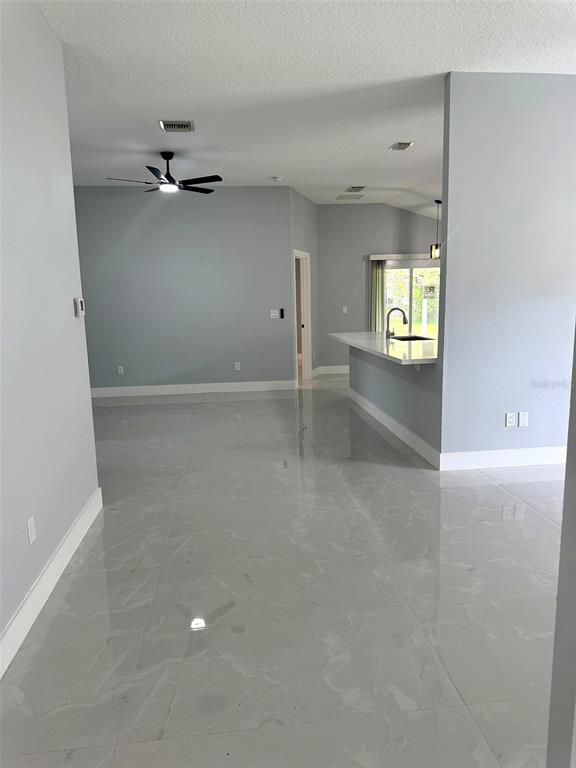 An open-concept living area features light gray walls, white trim, and glossy marble-look tile flooring — 12 N REYNOLDS PLACE, PALM COAST, FL