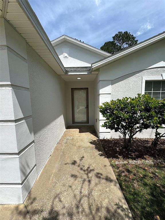 A concrete walkway leads to the front entrance of a white stucco house — 12 N REYNOLDS PLACE, PALM COAST, FL