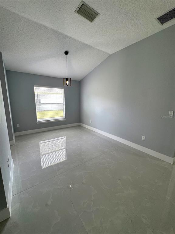 A bright room with light gray walls, large white floor tiles, and a hanging pendant light — 12 N REYNOLDS PLACE, PALM COAST, FL