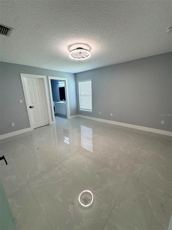 A bedroom with light gray walls, white trim, and large, glossy marble-patterned floor tiles — 12 N REYNOLDS PLACE, PALM COAST, FL