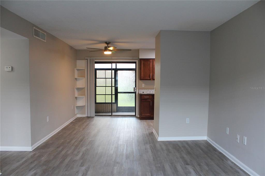 This living area features gray wood-look flooring, a ceiling fan, built-in shelves, and a sliding door — 1920 E EDGEWOOD DRIVE UNIT D9, LAKELAND, FL