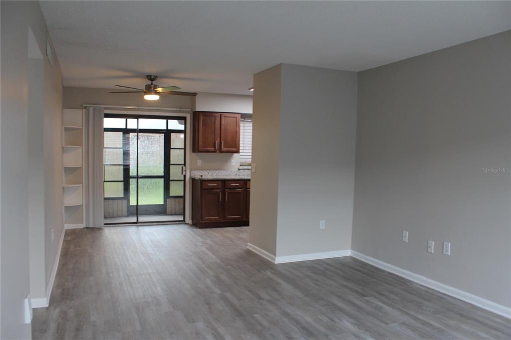 An open-concept living area features gray walls, wood-look flooring, and a kitchen with dark cabinets — 1920 E EDGEWOOD DRIVE UNIT D9, LAKELAND, FL