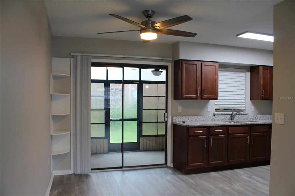 A kitchen with dark wood cabinets, granite countertops, and a sliding glass door to a patio — 1920 E EDGEWOOD DRIVE UNIT D9, LAKELAND, FL