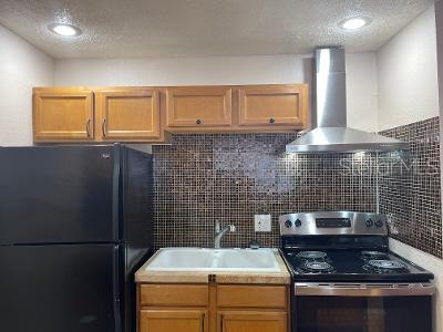 A kitchen with wood cabinets, a black refrigerator, a stove, and a tiled backsplash — 9105 W HILLSBOROUGH AVENUE UNIT I104, TAMPA, FL