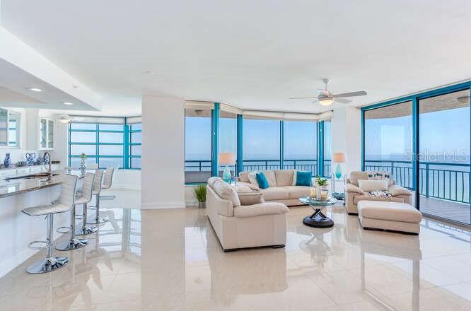 A bright, open-concept living room and kitchen with floor-to-ceiling windows overlooking the ocean — 1520 GULF BOULEVARD UNIT 1602, CLEARWATER BEACH, FL